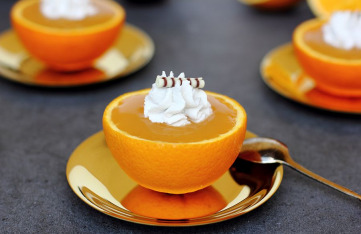 Zitronen-Orangen-Gelee mit Kokos-Creme, serviert in einer Orangenhälfte auf silbernem Unterteller