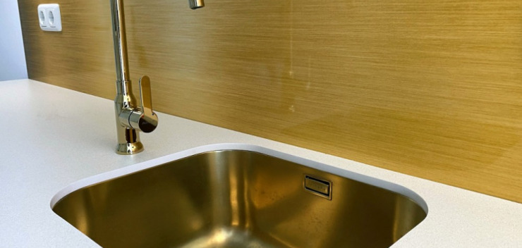 goldfarbene Unterbauspüle mit goldenem Wasserhahn eingebaut in eine weiße Compact-Arbeitsplatte in einer Mini-Küche in Berlin