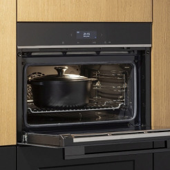 geöffneter schwarzer Siemens Kompaktbackofen in einer Nolte Küche mit hellen Holzfronten
