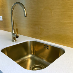 goldfarbene Unterbauspüle mit goldenem Wasserhahn eingebaut in eine weiße Compact-Arbeitsplatte in einer Mini-Küche in Berlin