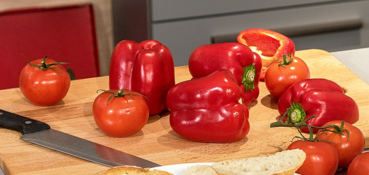 Holzbretter mit roten Tomaten und Paprikaschoten und Schneidemesser