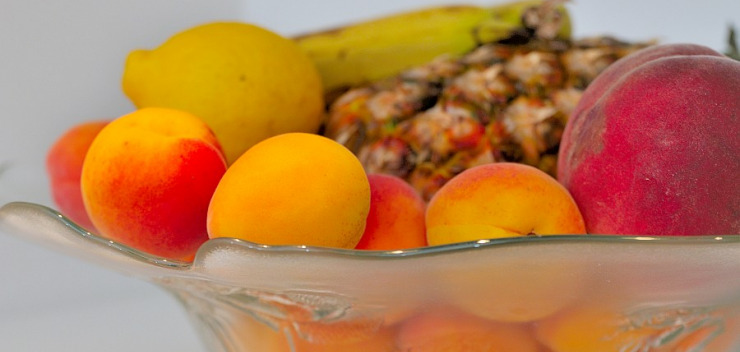 Obstschale mit Aprikosen, Pfirsich, Zitrone und Ananas