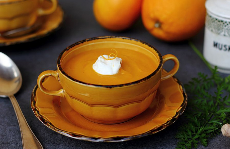 Karottensuppe mit Orangen-Topping in gelber Keramikschüssel