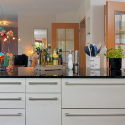 Küchentheke als Raumteiler Beispiel weiß mit Griffen und schwarzer Granit-Arbeitsplatte