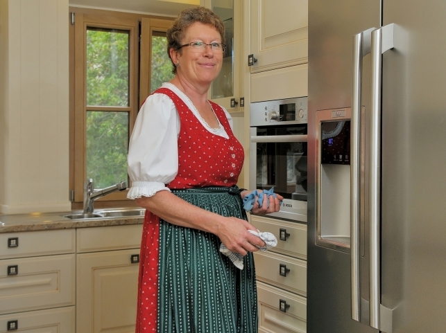 Seniorin aus Süddeutschland, glücklich beim Putzen ihrer Küche