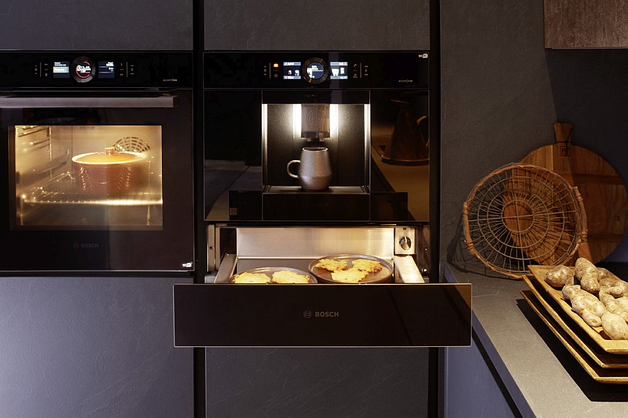 Küchenfront mit Bosch-Einbaugeräten Backofen, Kaffeevollautomat und darunter eine geöffnete Wärmeschublade