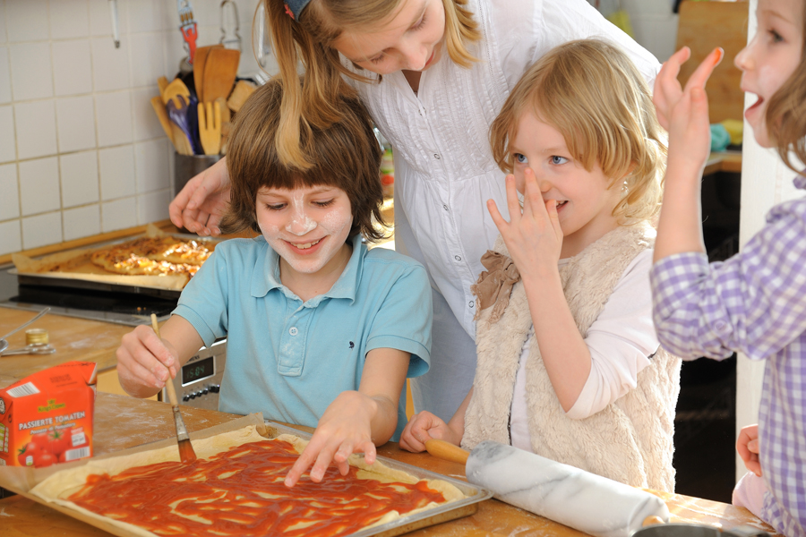Kinder backen Pizza auf einem Backblech