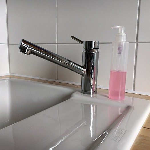 Spülmittelflasche aus Plastik auf weisser Keramikspüle
