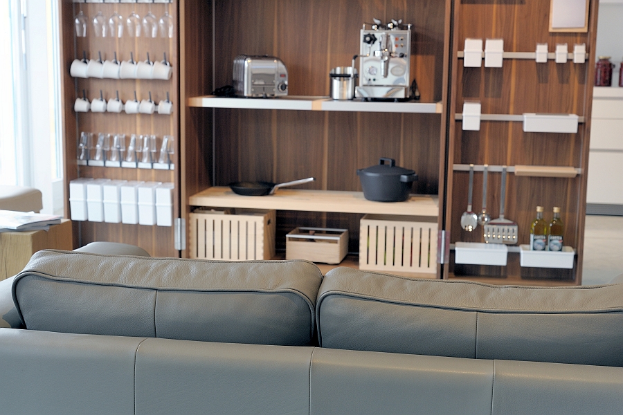 Aufgeklappter Küchenwerkschrank mit Kochzubehör, Essgeschirr, Kaffeemaschine und Toaster