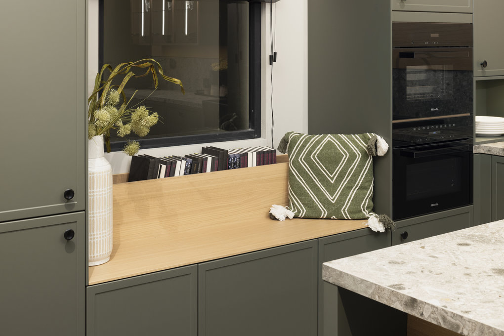 Sitznische am Fenster zwischen Hochschränken in olivgrüner Häcker-Küche